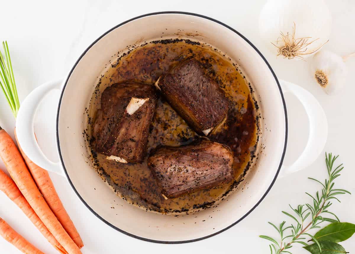 Beef short ribs in a white pot.