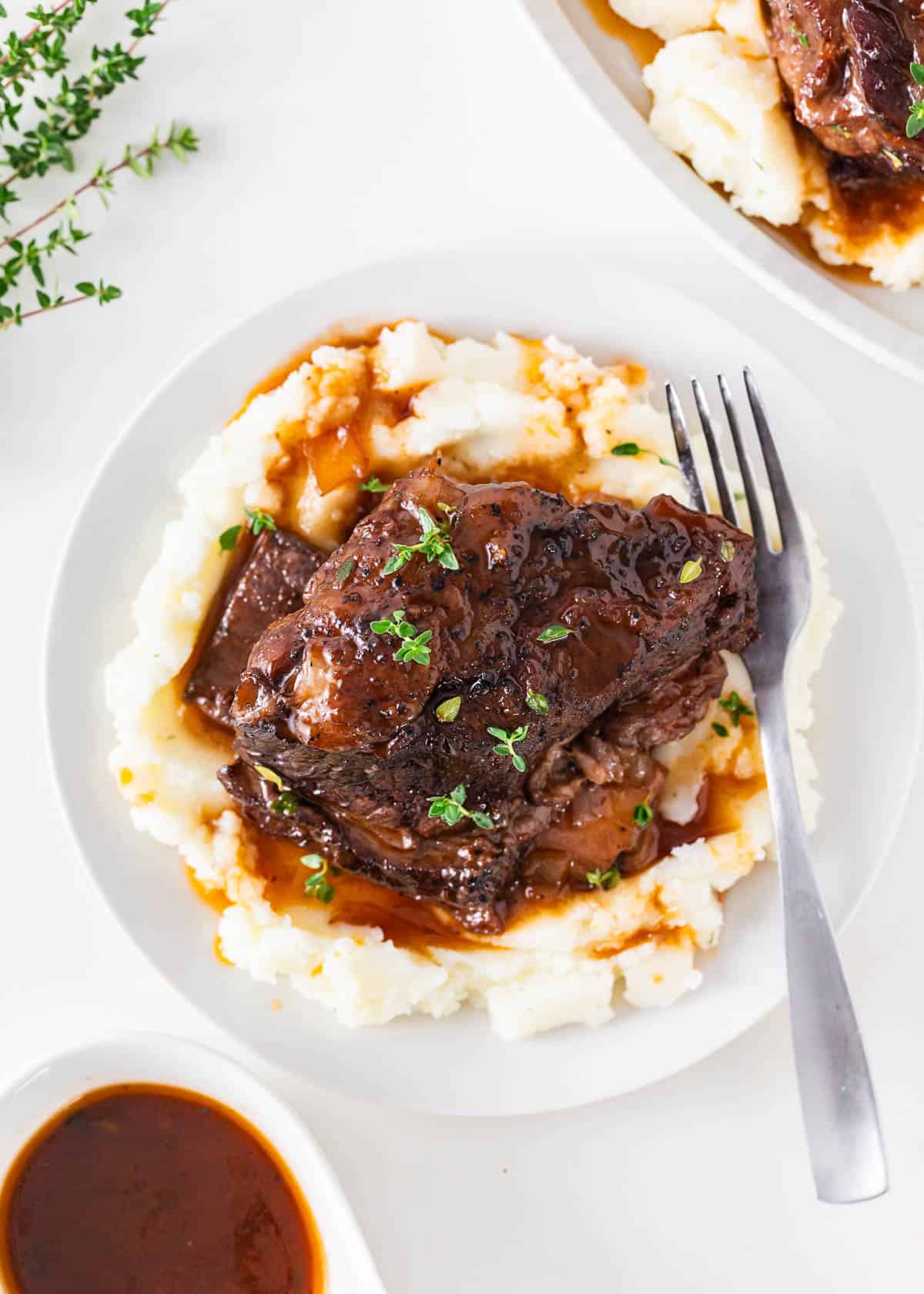 Braised short ribs served on a plate of mashed potatoes.