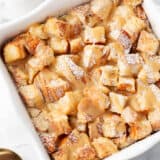 Bread pudding with caramel sauce in a white baking dish.