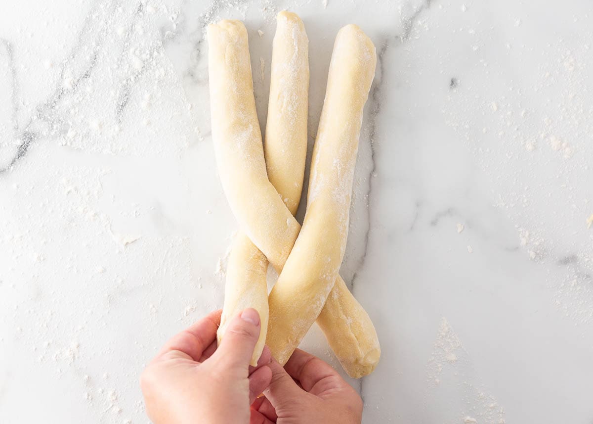 Three strands of brioche dough being braided. 