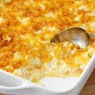 Spoonful of cheesy potatoes in a white baking dish.