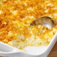 Spoonful of cheesy potatoes in a white casserole dish.