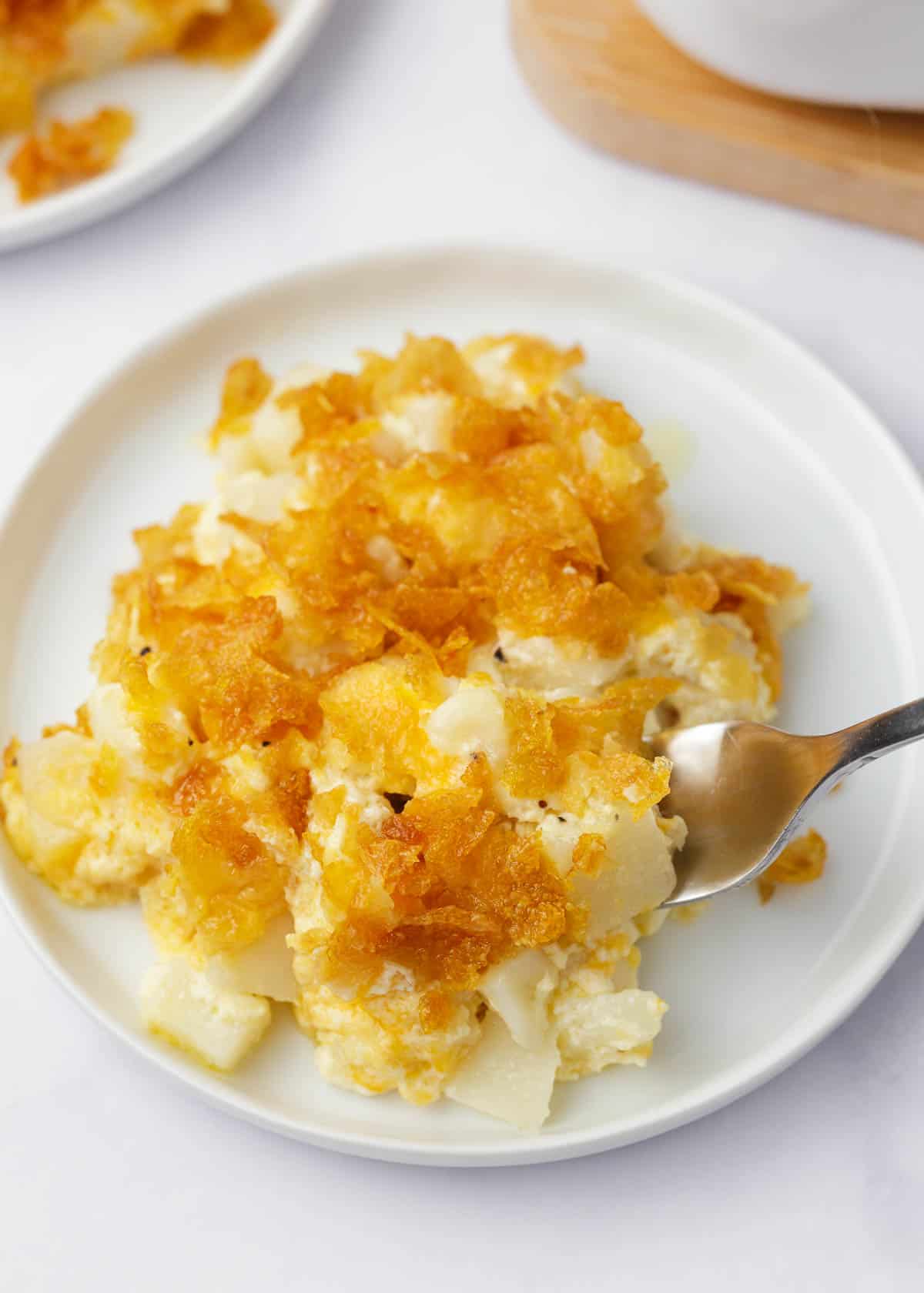 A white plate with a serving of cheesy potatoes.