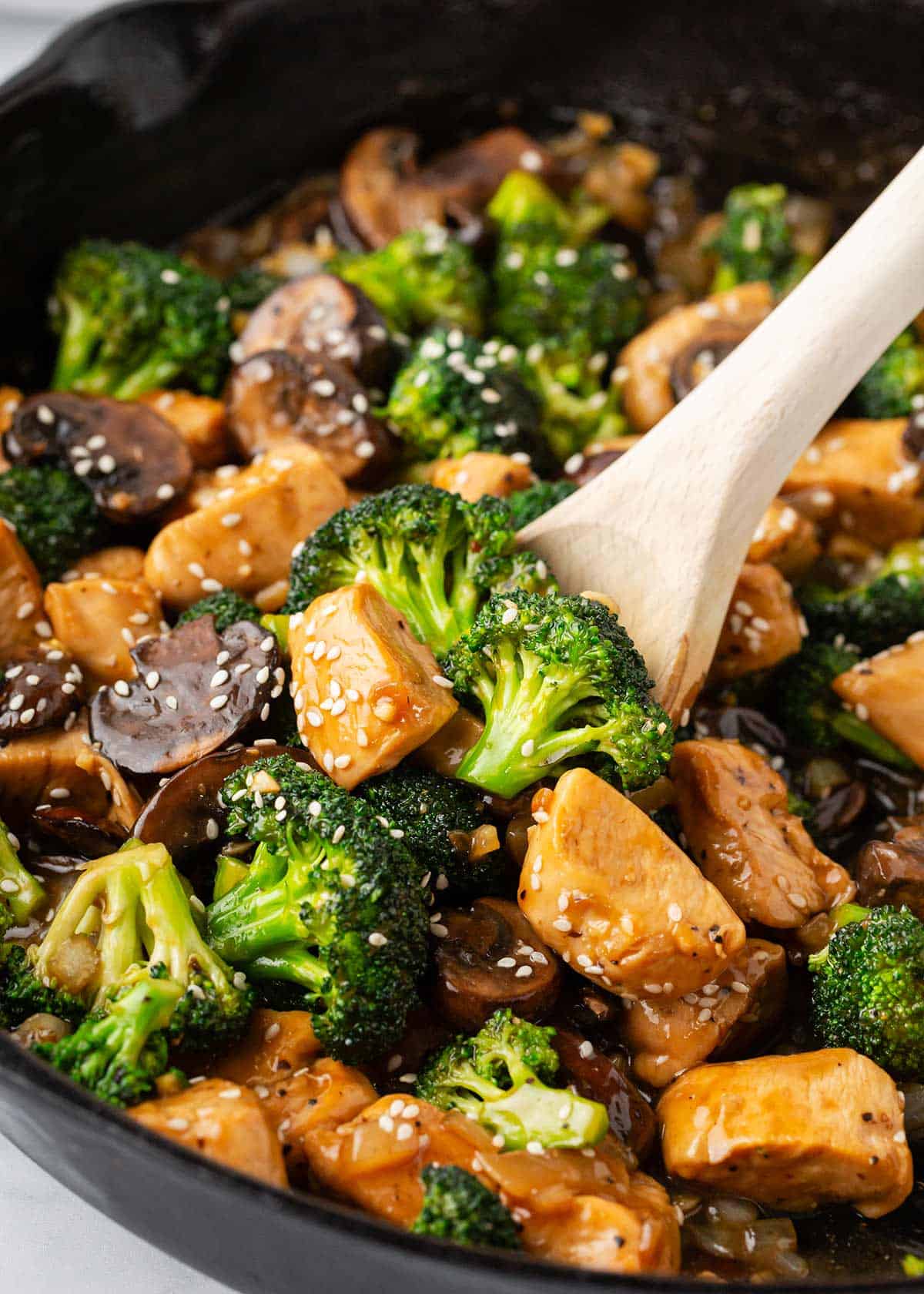 Chicken and broccoli stir fry cooking in a skillet. 