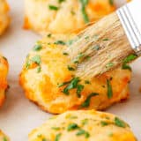 Brushing butter onto Red Lobster Cheddar Bay Biscuits.
