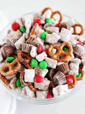 A close up of reindeer chow with powdered sugar cereal pieces, pretzels, peanut butter cups, and red and green M&M&rsquo;s mixed together.