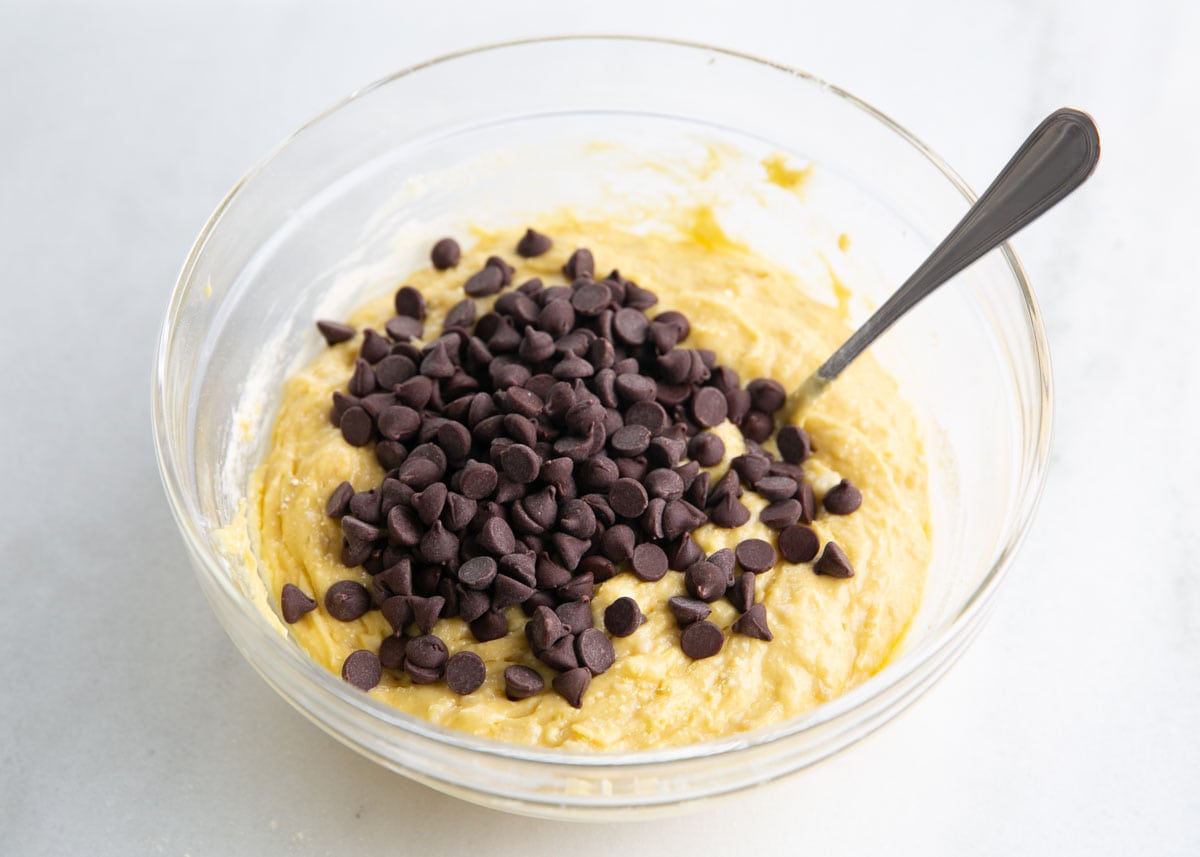 Stirring chocolate chips into yellow cake mix batter.