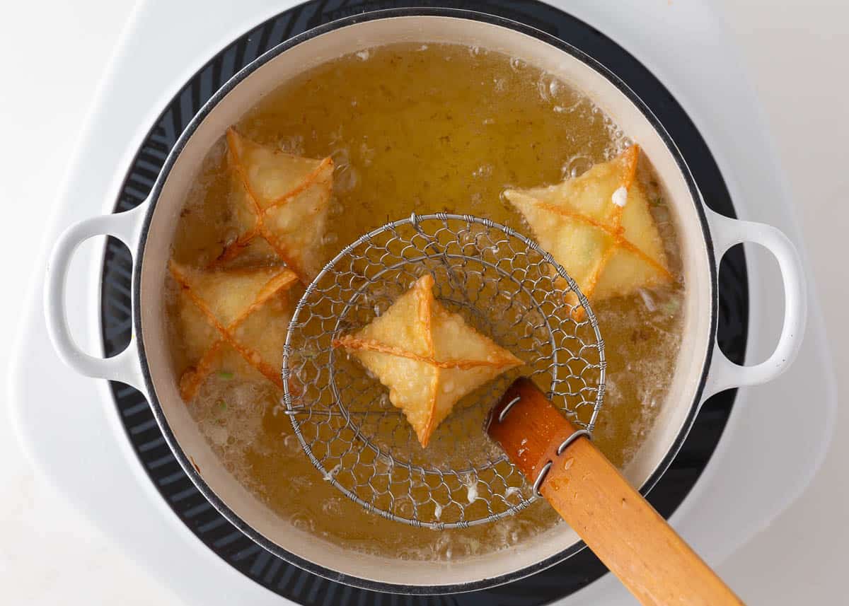 Deep frying crab rangoons until crispy. 