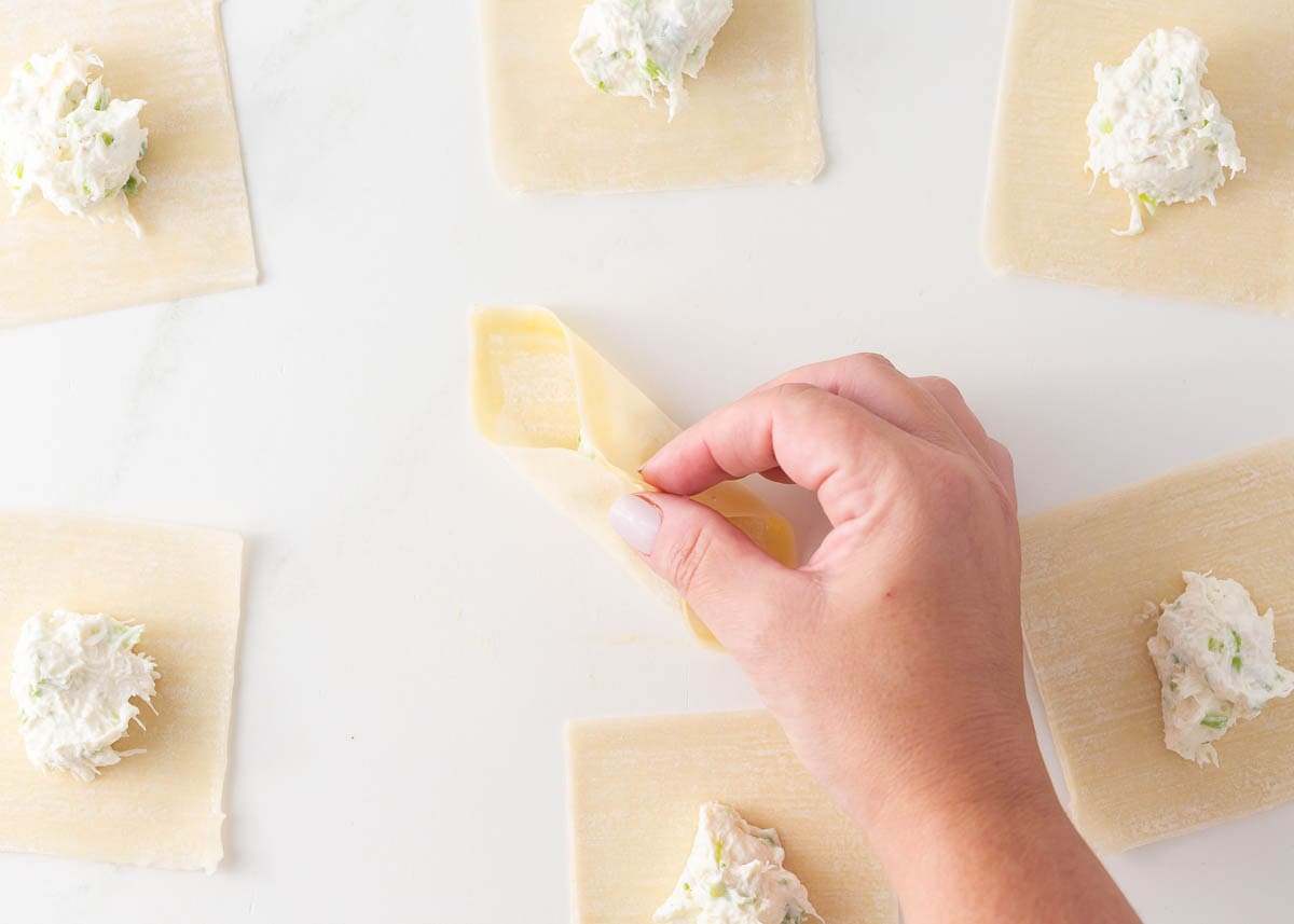 Showing how to fold wontons around cream cheese filling.