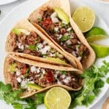 Barbacoa tacos on a plate.
