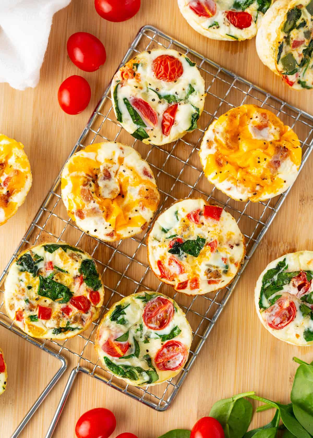 Easy-to-customize egg white muffins that make the perfect healthy on-the-go breakfast. They're high in protein, low in fat and downright delicious! Assorted egg white muffins cooling on a rack, each filled with colorful veggies and melted cheese.