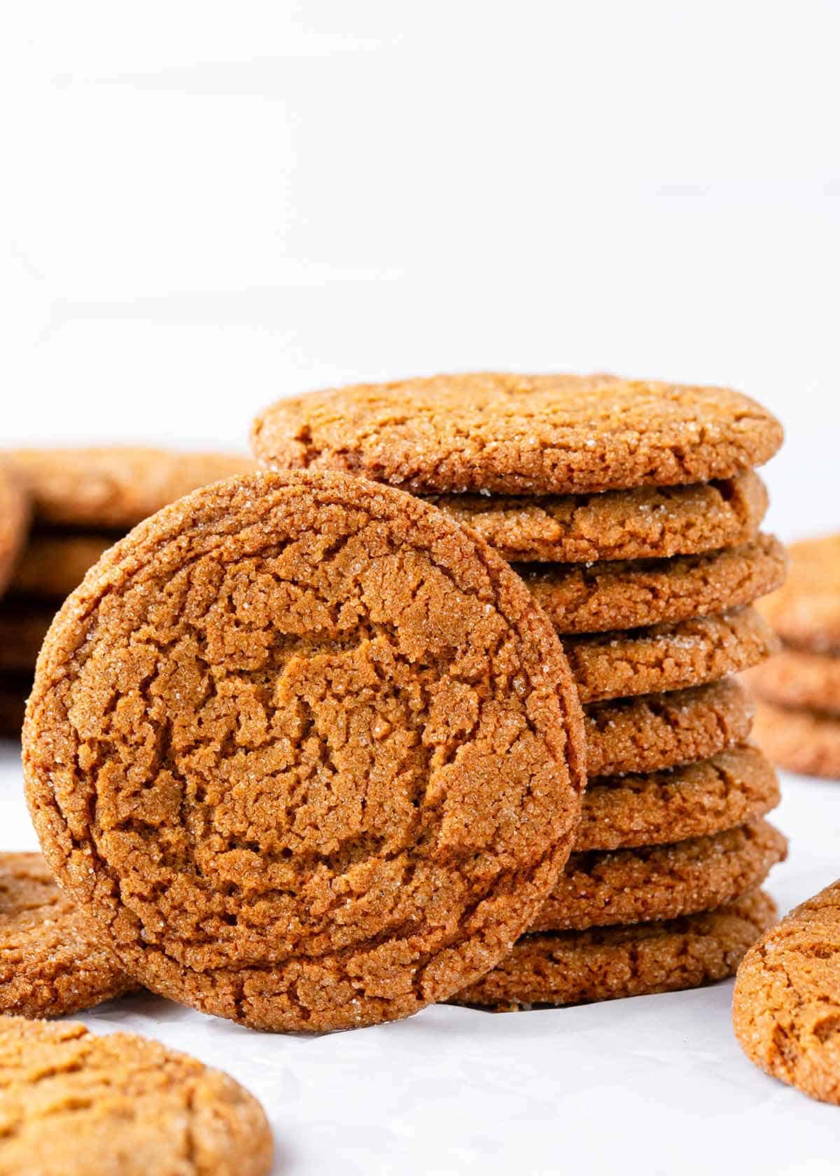 These gingersnap cookies are thin and crispy with crunchy edges and crackly tops! A holiday classic that's easy to make with flavorful warm spices and molasses. A stack of crispy gingersnap cookies.