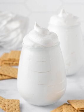 Homemade marshmallow fluff in glass jars with graham crackers.