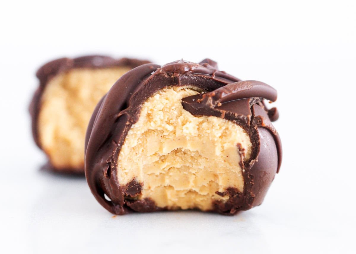 Close-up of a chocolate-dipped peanut butter ball with a bite taken out, showing the creamy peanut butter center.
