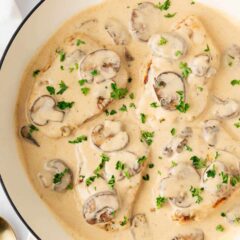 Smothered pork chops cooked in a skillet.