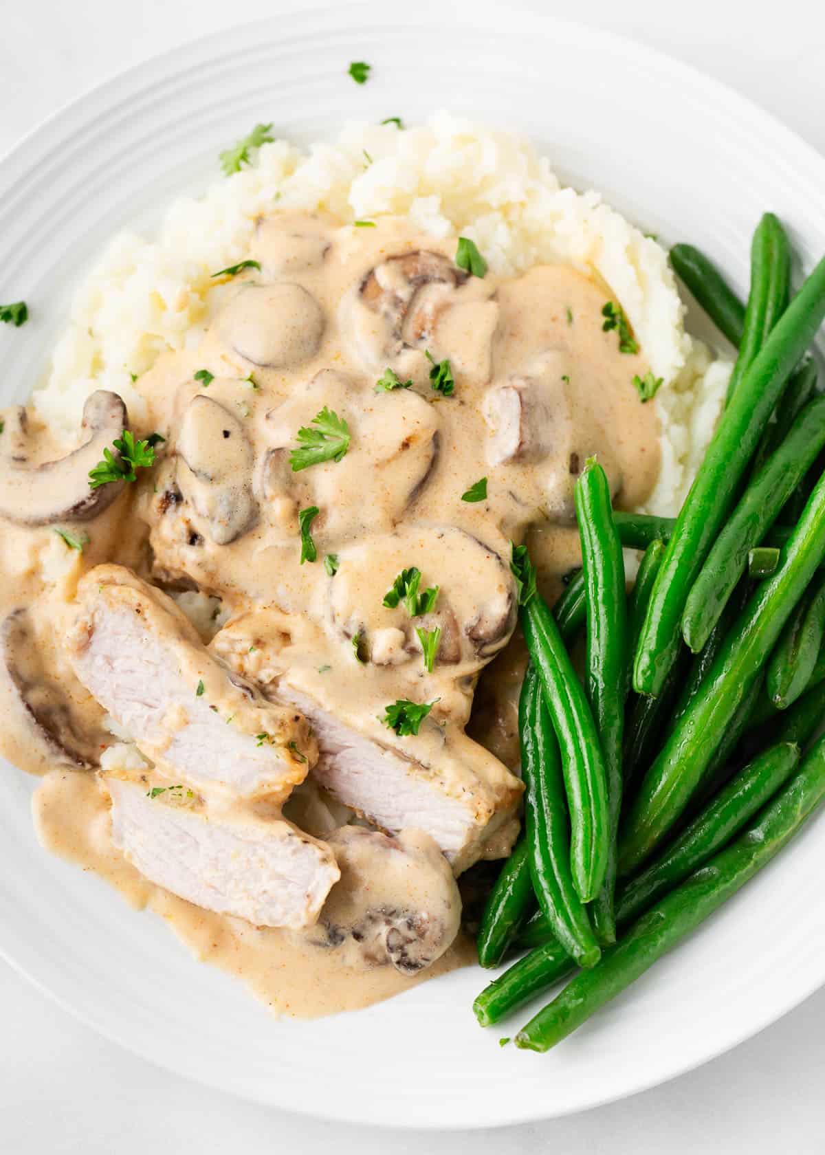 Smothered pork chops with mashed potatoes and green beans.