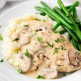 Smothered pork chops with mashed potatoes and green beans.