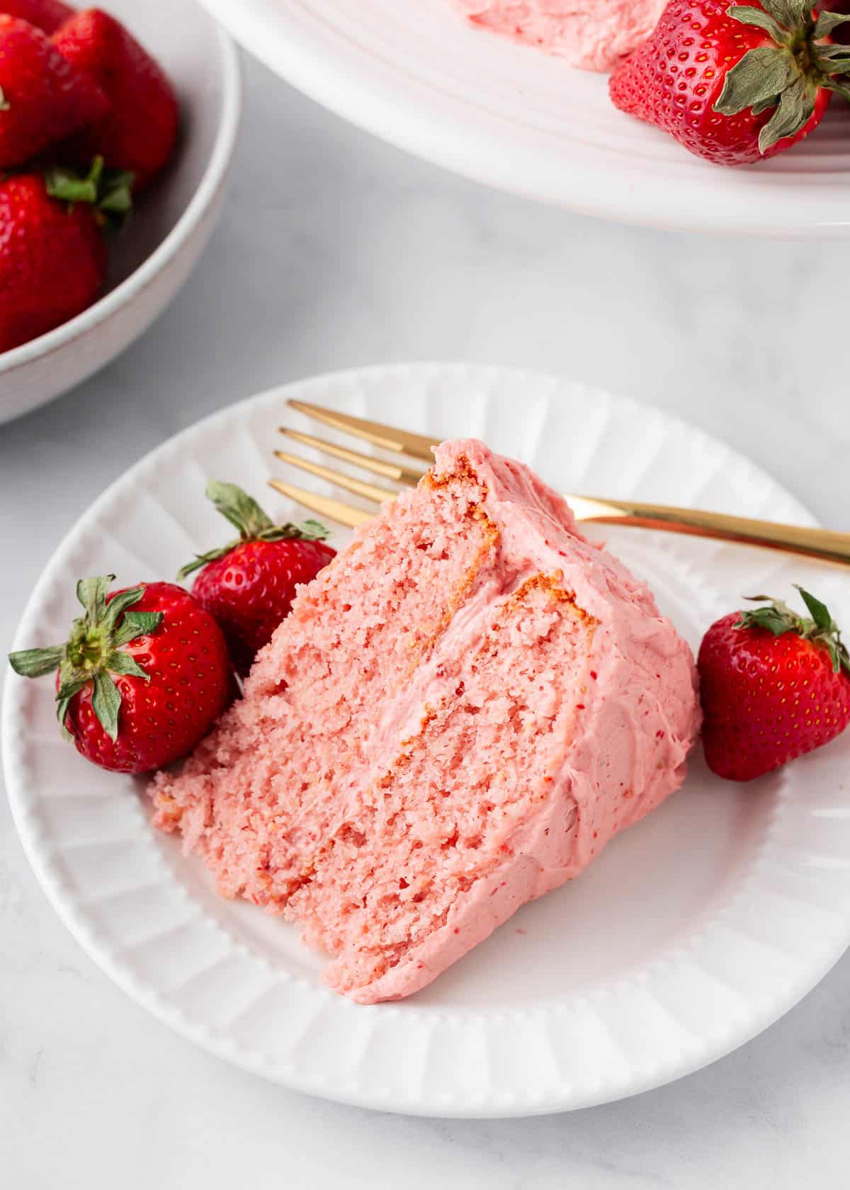 Slice of strawberry cake with fresh strawberries.