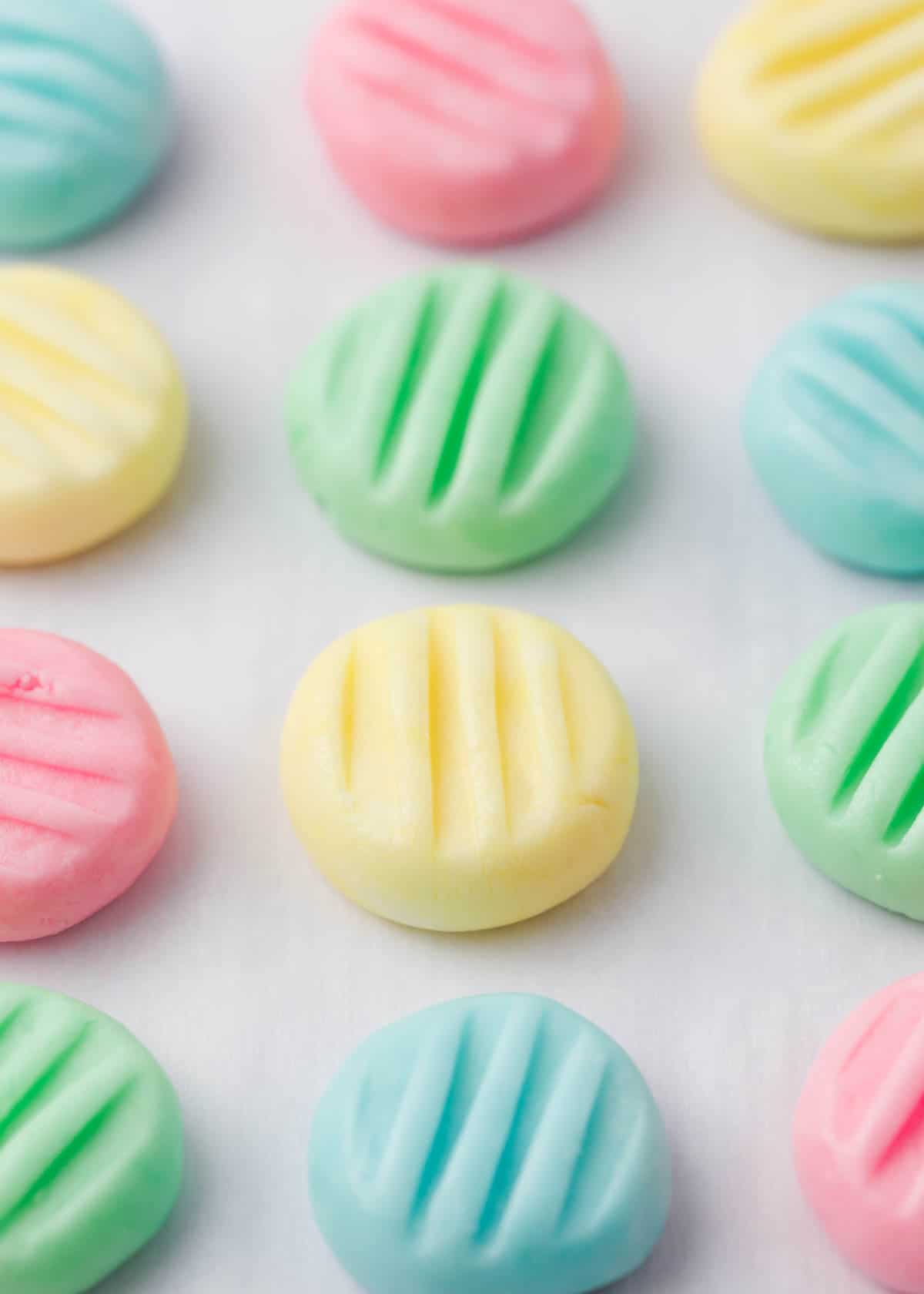 Melt-in-your-mouth old-fashioned cream cheese mints are easy to make with only 4 ingredients. Change candy flavor or color to suit any special holiday or occasion. Best cream cheese mints in pastel colors on a counter.