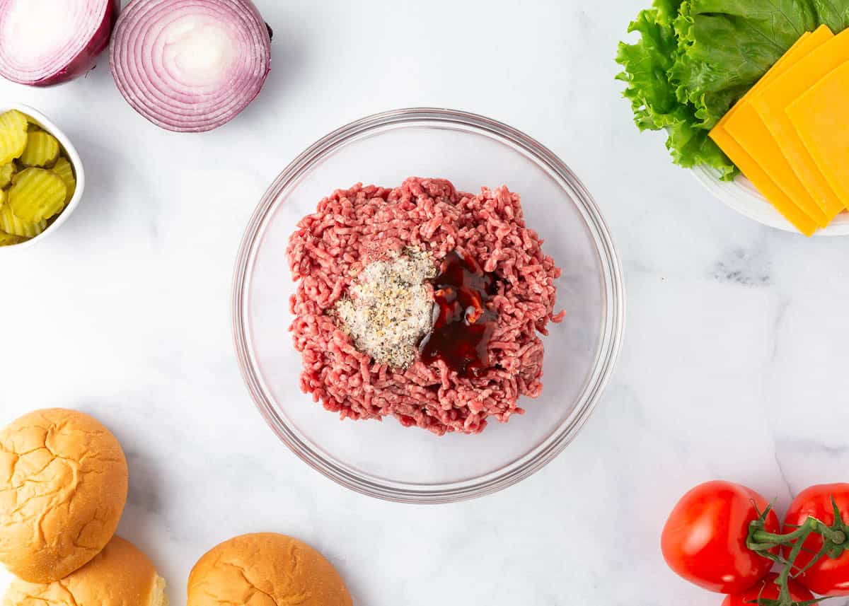 Ground beef mixed with seasoning in a bowl to make easy oven baked hamburgers.