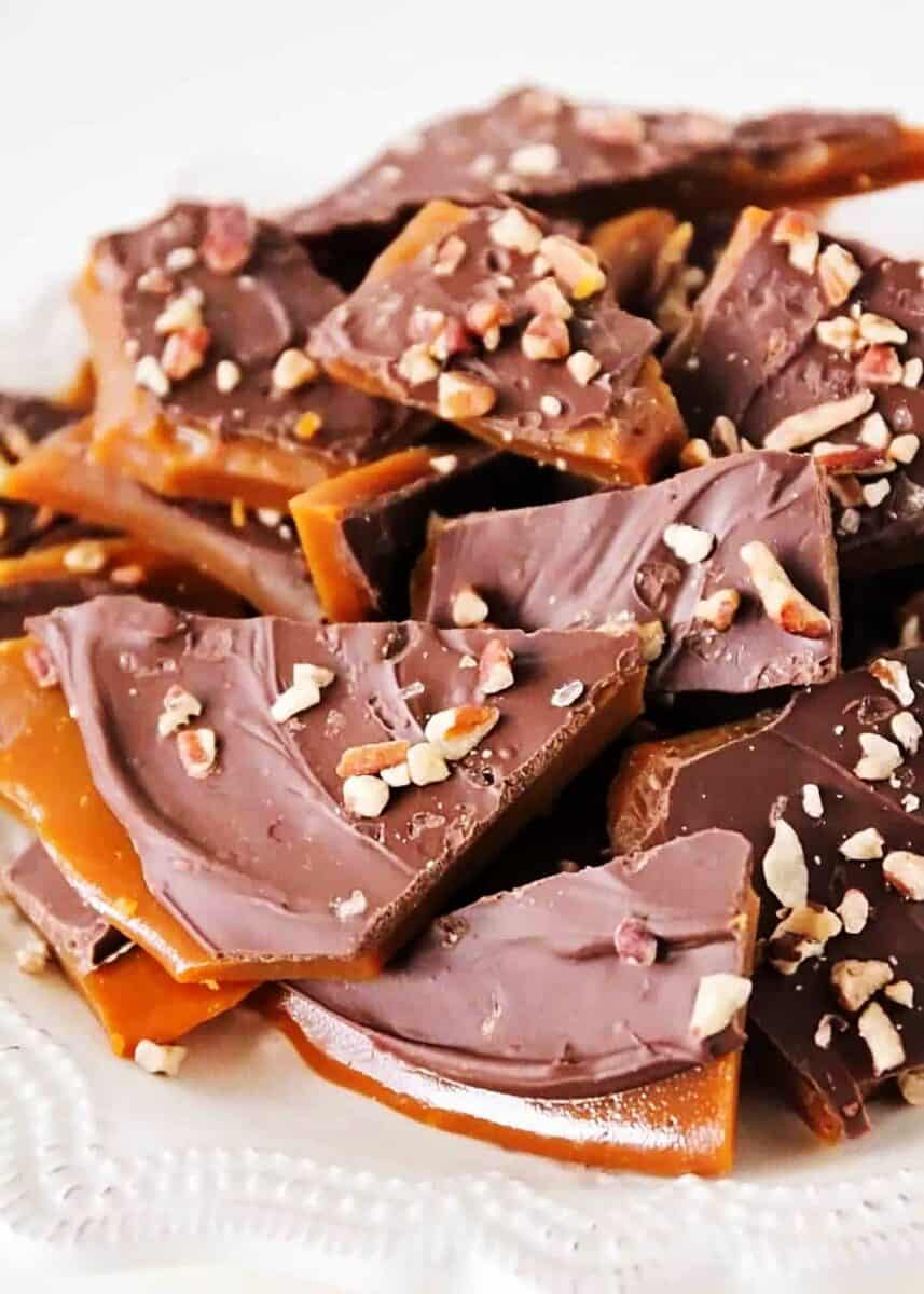 My easy 30-minute homemade toffee recipe makes a rich, buttery, crunchy toffee. It has a sweet chocolate topping with toasted nuts that's perfect for parties, gifts, and snacking. Best toffee recipe on a white plate.