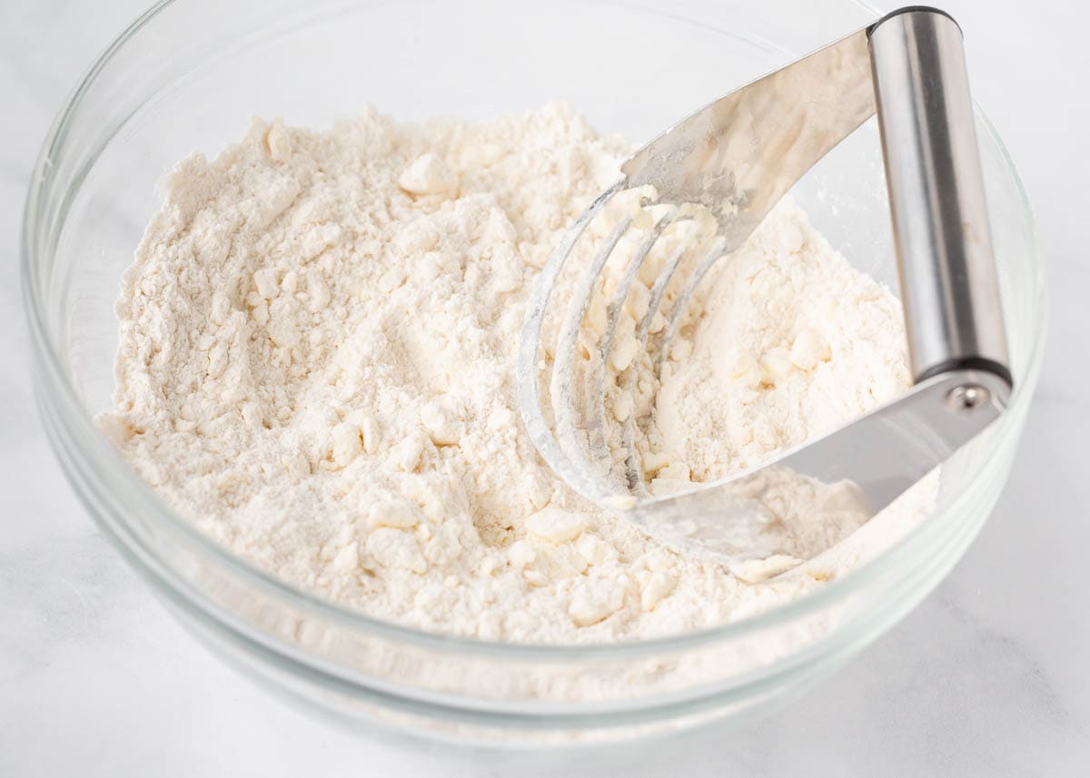 Using a pastry cutter to cut butter into flour.