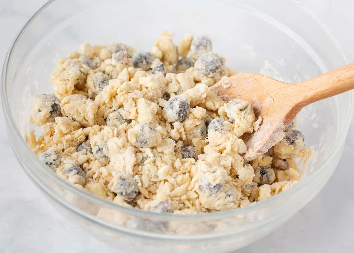 Scone dough with blueberries in a glass bowl.