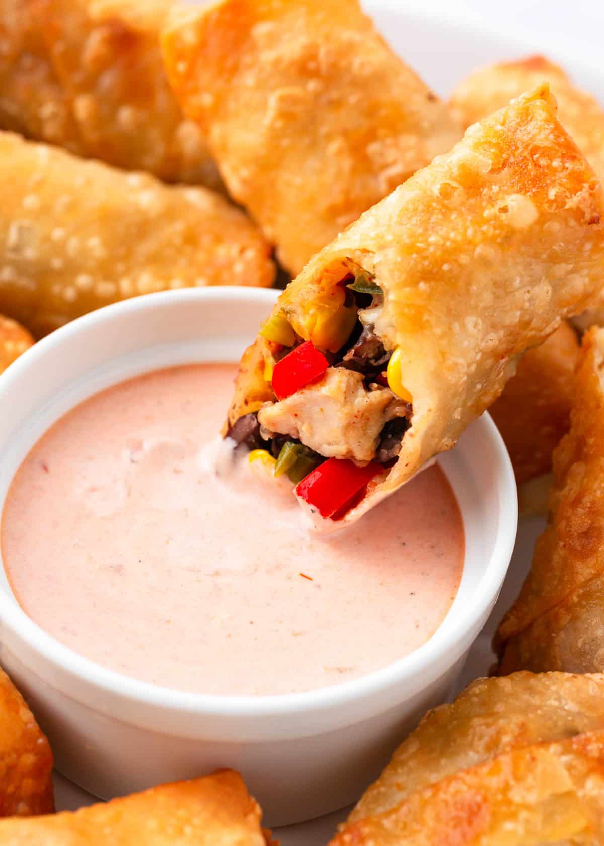 Southwest egg roll dipped into a bowl of sauce.