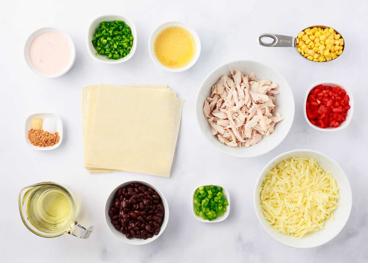 Southwest egg rolls ingredients on marble counter.