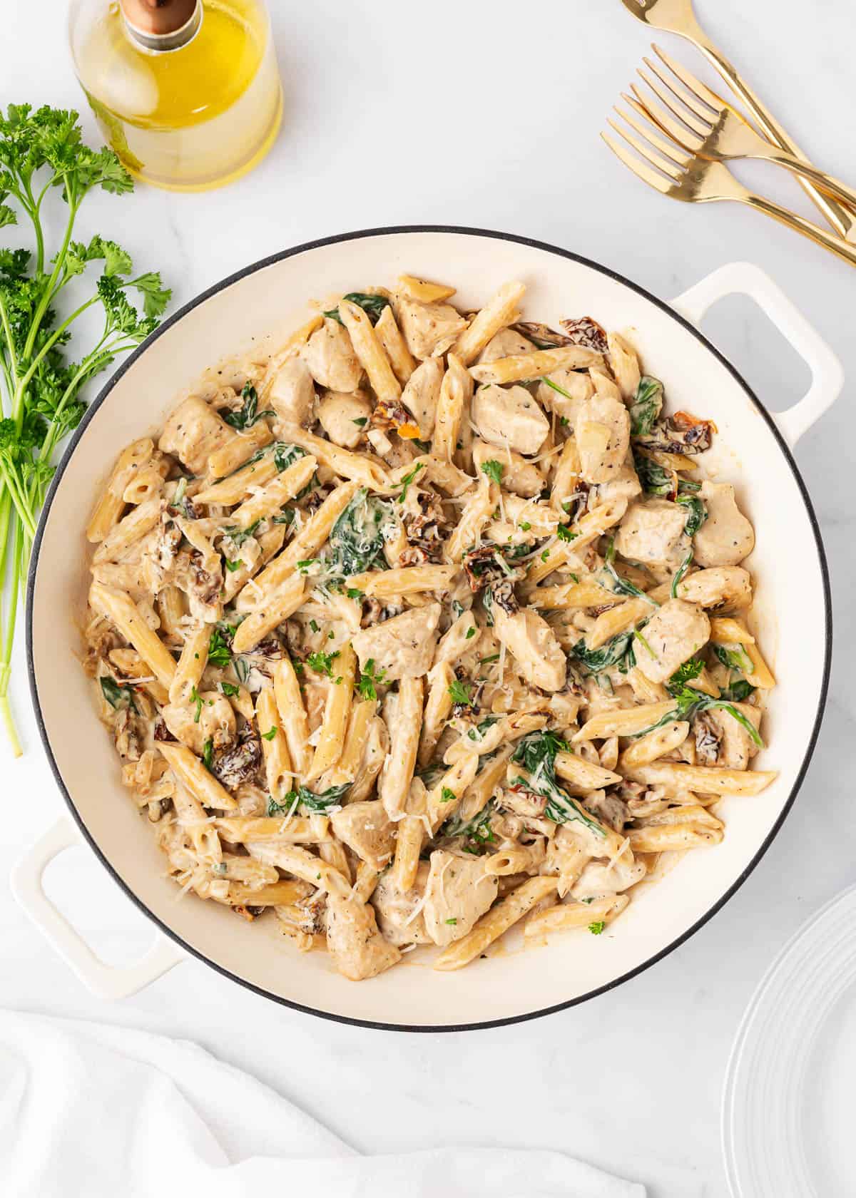 Creamy Tuscan chicken pasta is easy to make in 30 minutes with juicy chicken, spinach, and sundried tomatoes tossed in a cream sauce. It's a restaurant-style dish made in the comfort of your kitchen! Tuscan chicken pasta in a white pot.
