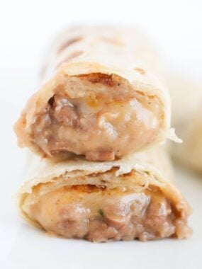 Bean and cheese burritos cut in half showing creamy refried bean and melted cheese filling.