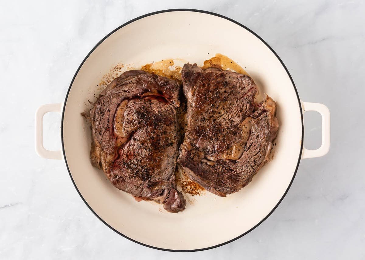 Steak searing in a hot cast-iron skillet for a golden crust.