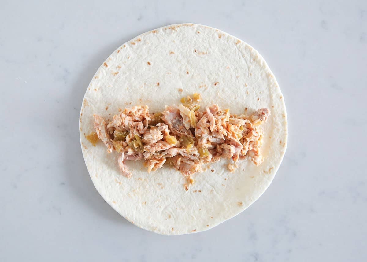 Chicken filling spread across the center of a flour tortilla.