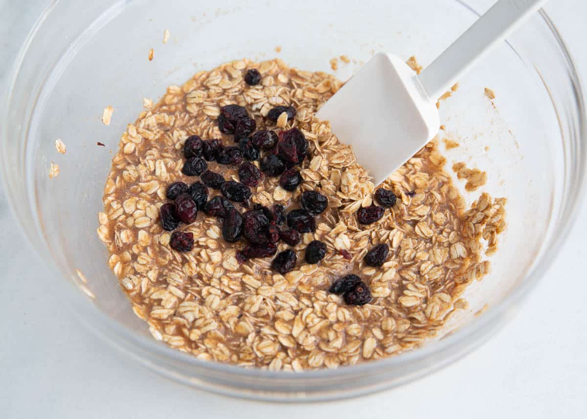 These oatmeal breakfast bars are soft, chewy and a healthy start to the day! They are quick and easy to meal prep in advance for breakfast and snacks. Oats, sugar, baking powder, salt, cinnamon and raisins stirred into liquid ingredients in a bowl.