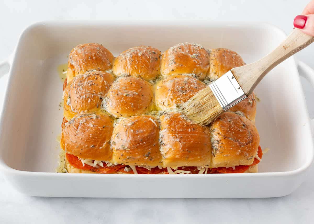 Hawaiian roll tops placed on pizza sliders and brushed with garlic butter and Italian seasoning