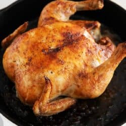 Whole roasted chicken in a cast iron pan.