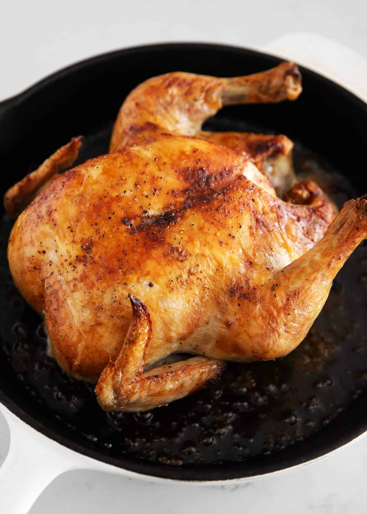Whole roasted chicken in a cast iron pan.