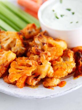 Roasted buffalo cauliflower bites served with celery sticks, carrots, and a creamy dipping sauce.