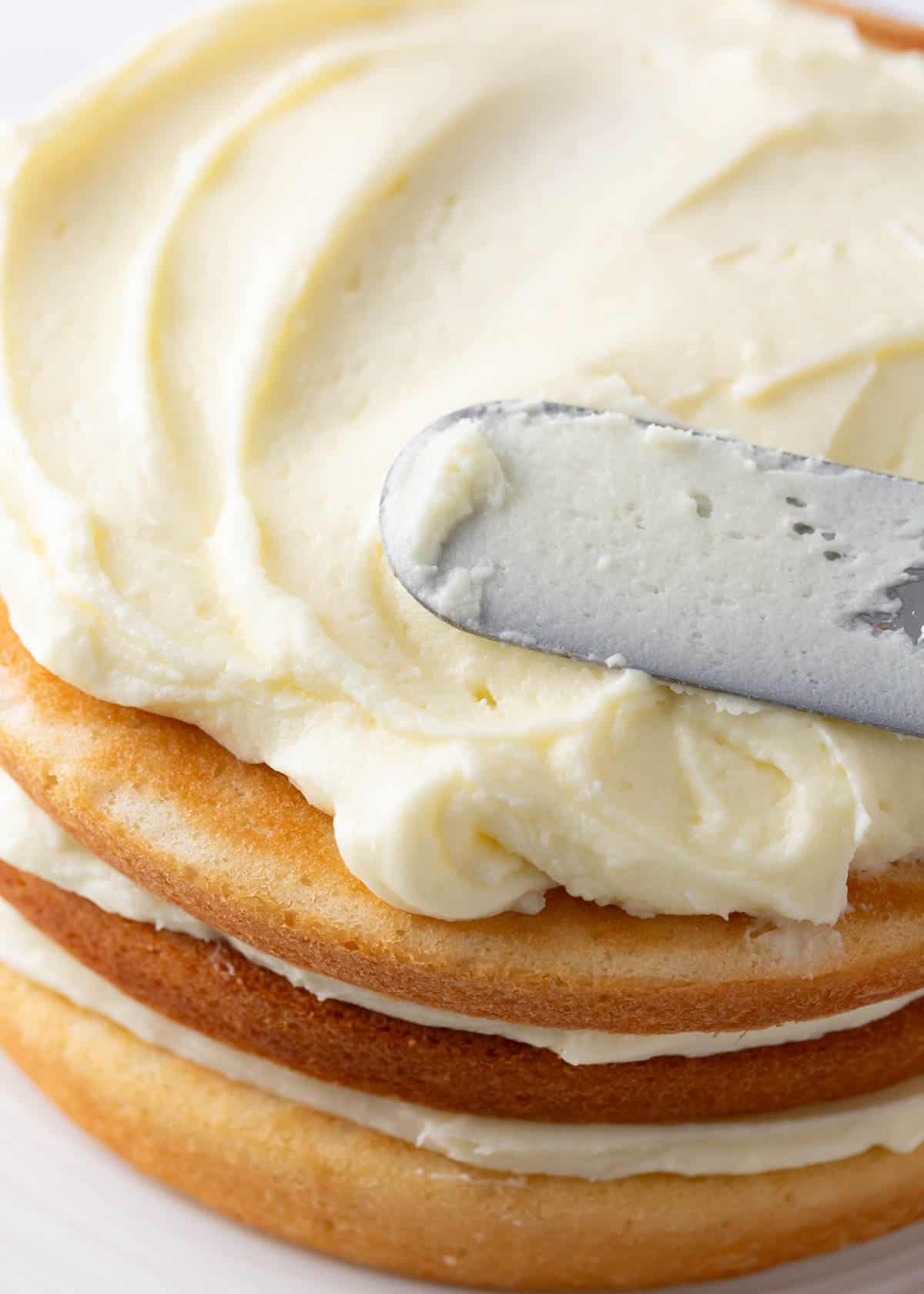 Spreading frosting onto a coconut cake.