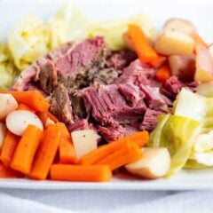 Slow cooked tender corned beef and cabbage on plate with carrots and potatoes.