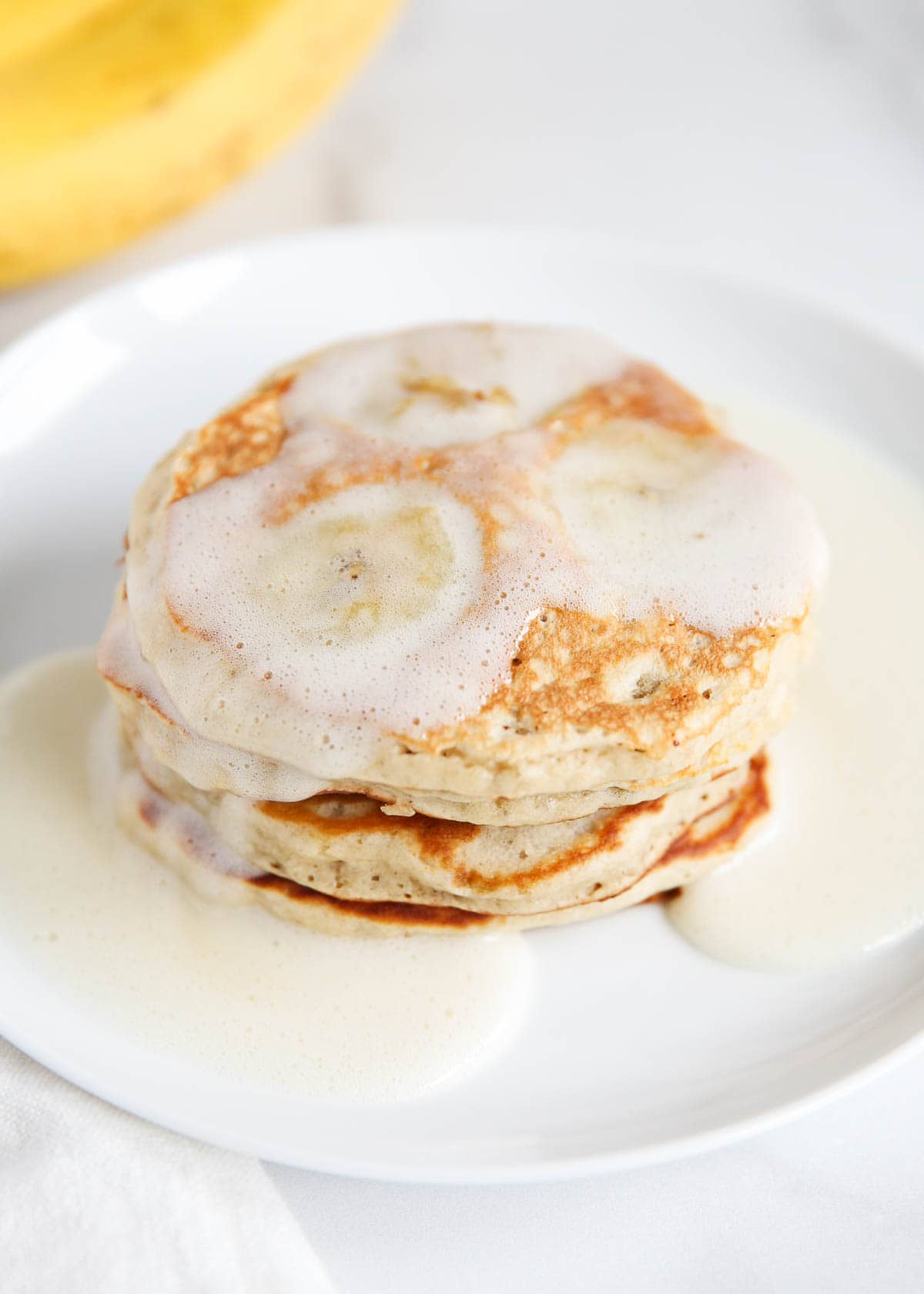 Banana pancakes on a white plate with syrup.