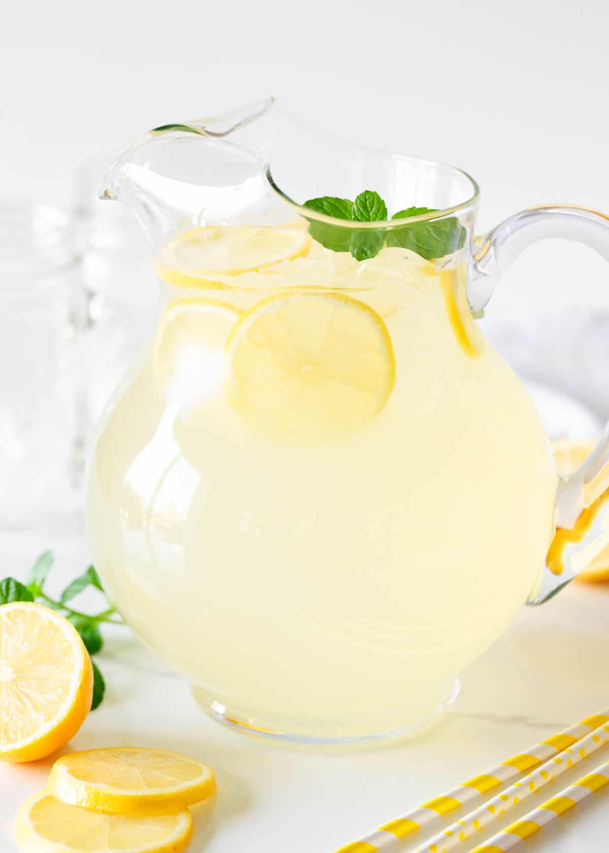 Learn to make a homemade lemonade recipe with fresh lemons and simple syrup. Enjoy a cool glass of this refreshing classic drink which is the perfect balance of sweet and tart! Homemade lemonade in a glass pitcher.