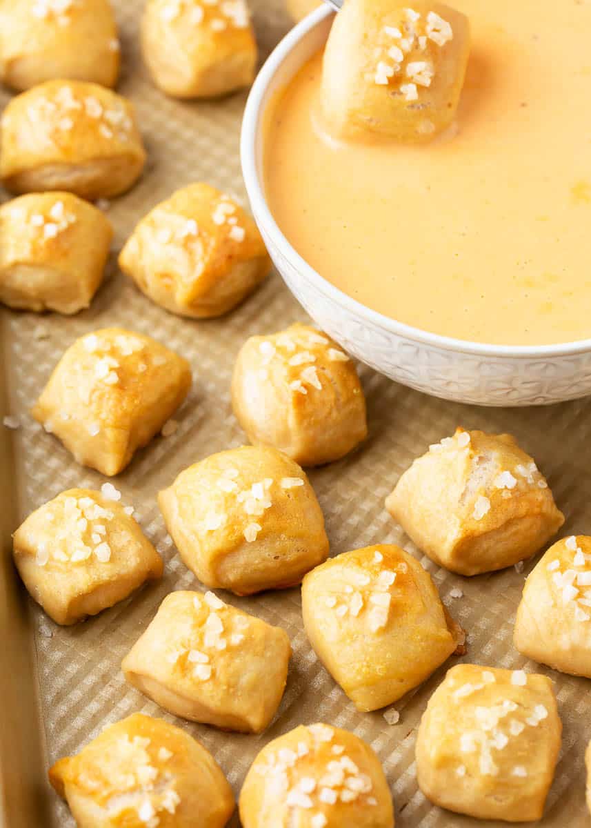 Pretzel bites and cheese sauce on pan.