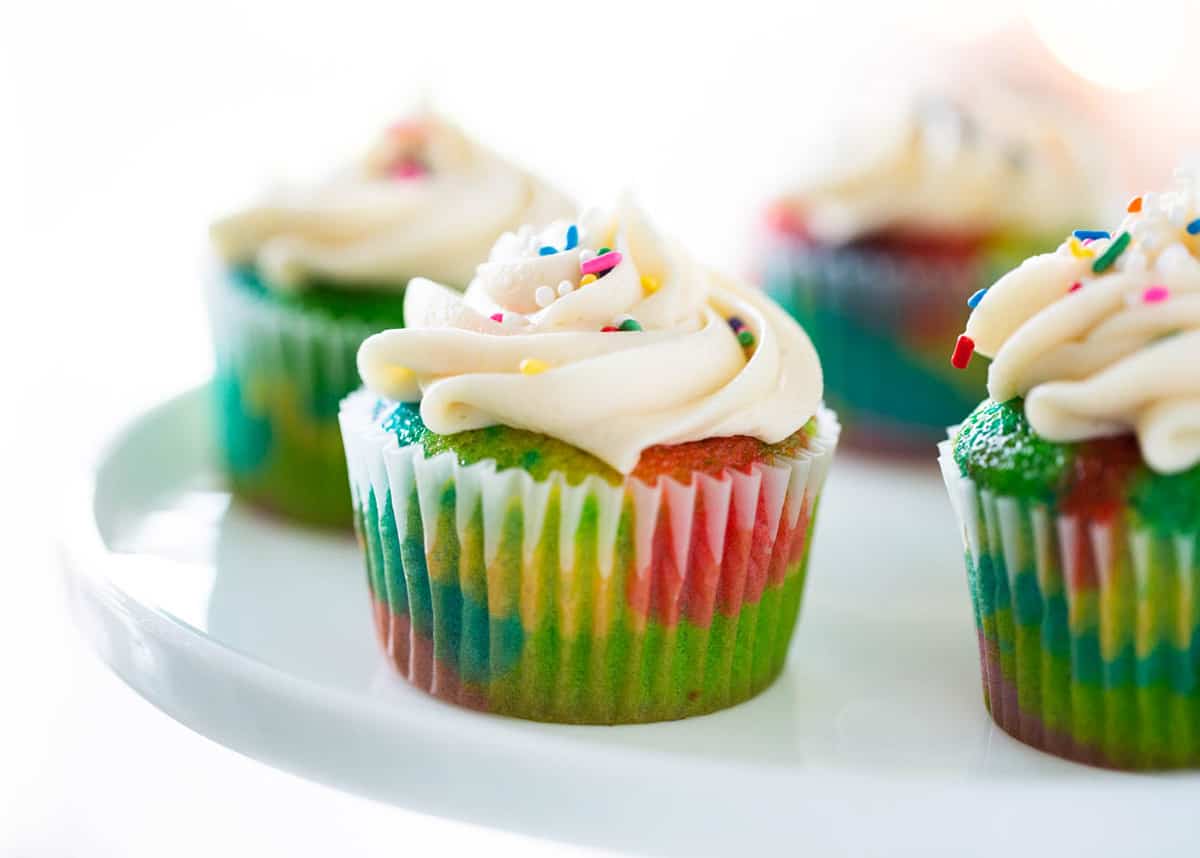 Rainbow cupcakes on cake stand.