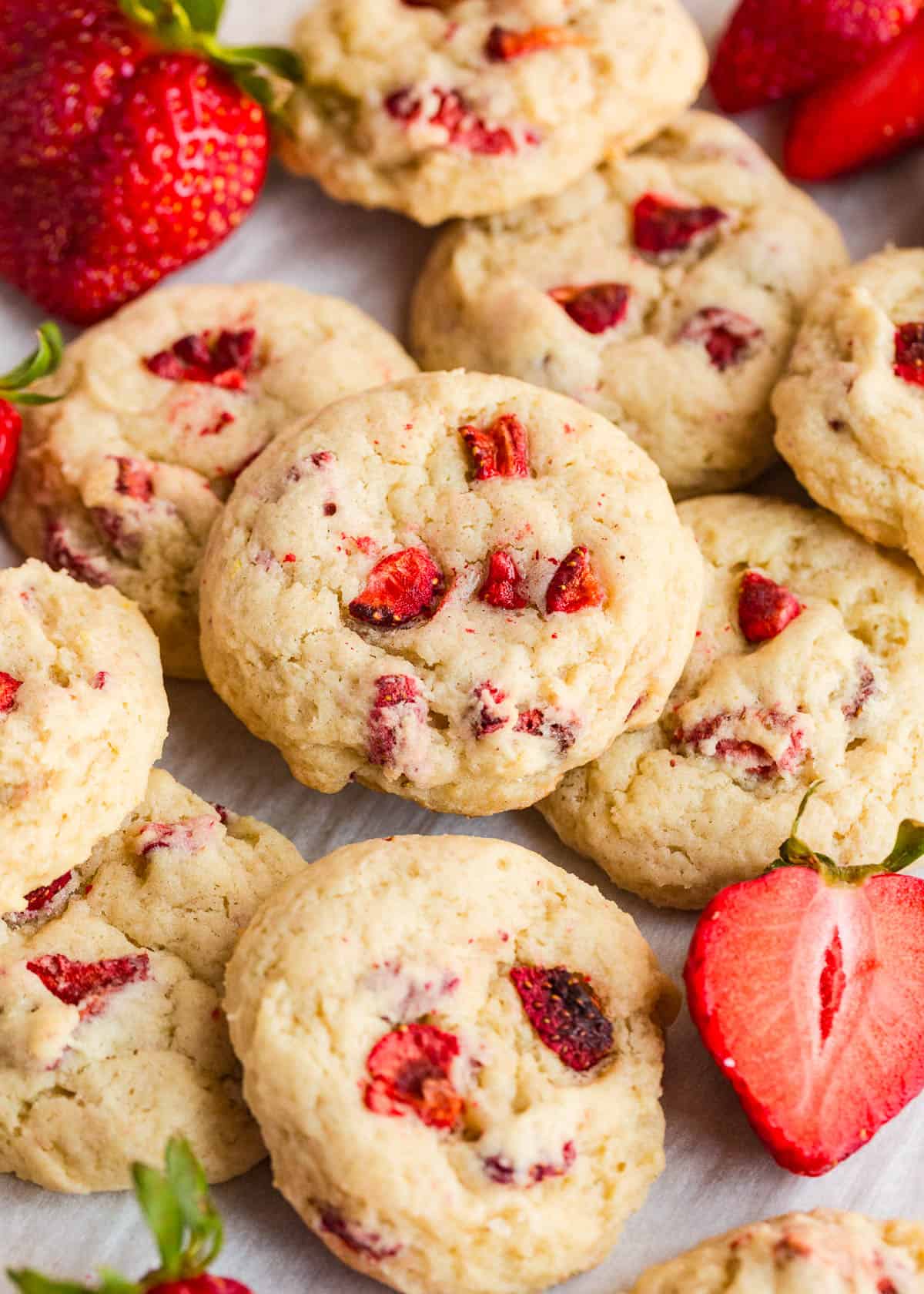 Stack of strawberry cookies with visible pieces of freeze dried strawberries on the counter.