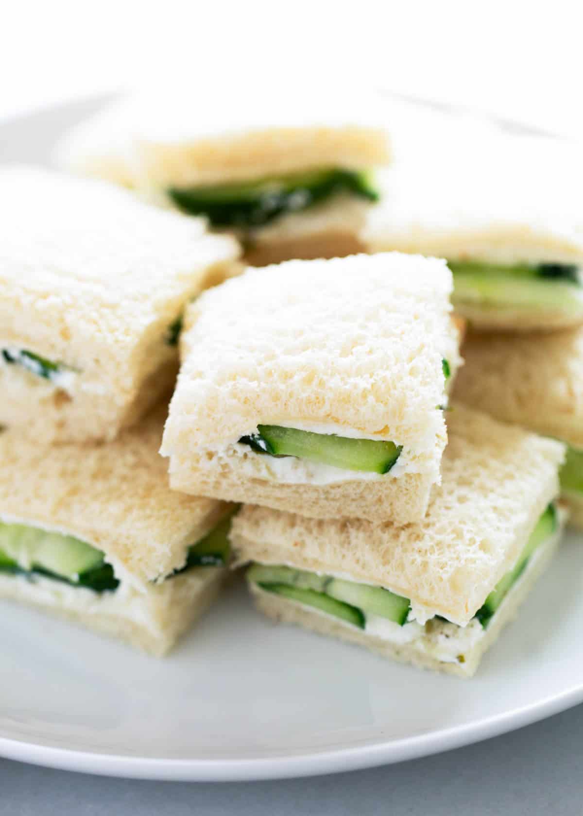 These cucumber sandwiches are a classic tea party appetizer perfect for a Mother's Day brunch, baby shower luncheon or bridal showers. Made with cream cheese and cucumbers on bread, it's a light and refreshing finger food. Stacked cucumber sandwiches.
