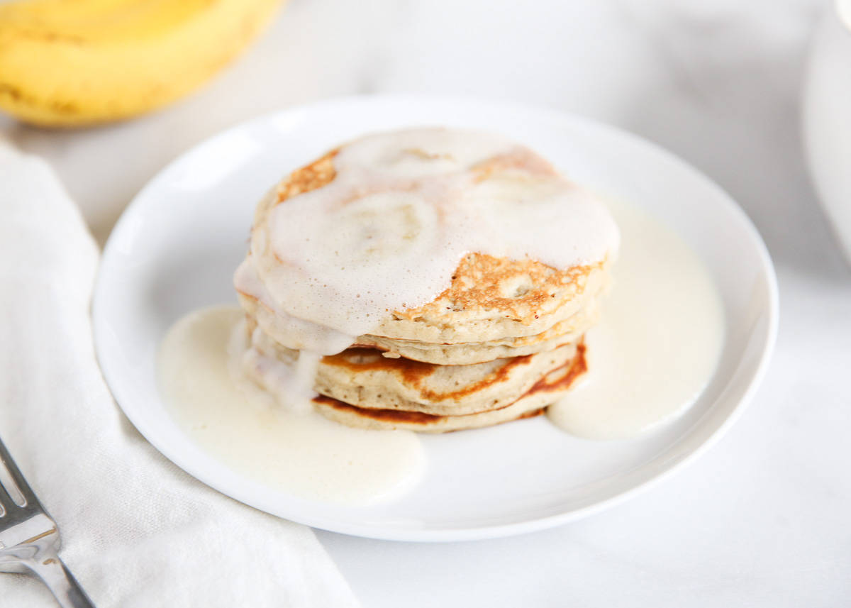 Easy banana pancakes on a white plate with syrup.
