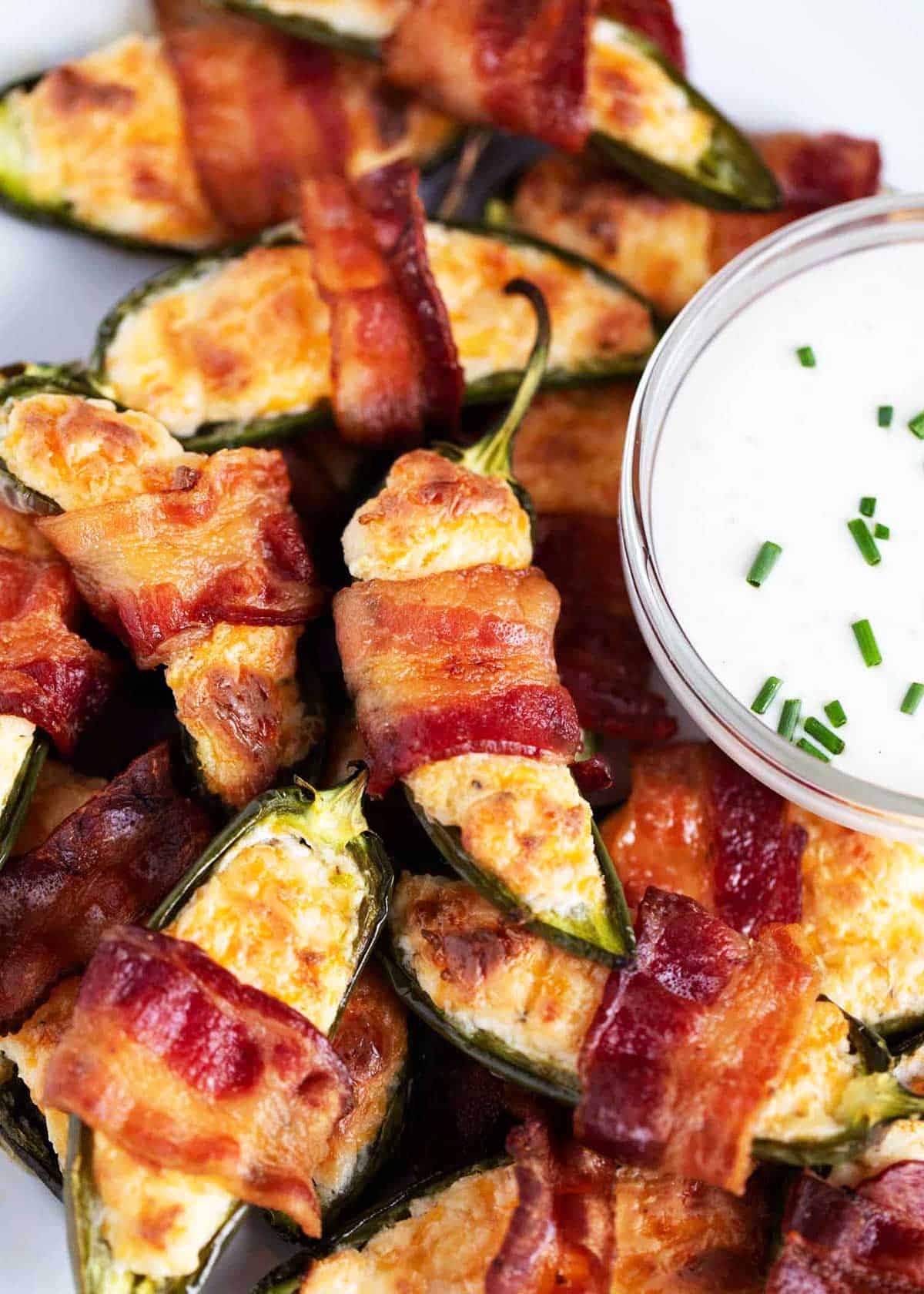 These jalapeño poppers are the perfect game day appetizer. Fresh halved jalapenos are stuffed with a rich cream cheese filling, wrapped in bacon and then baked for a craveable snack! Jalepeno poppers.