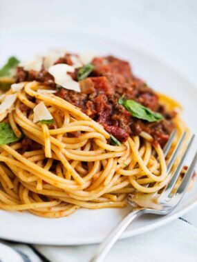 Spaghetti bolognese sauce with pasta on a white plate.