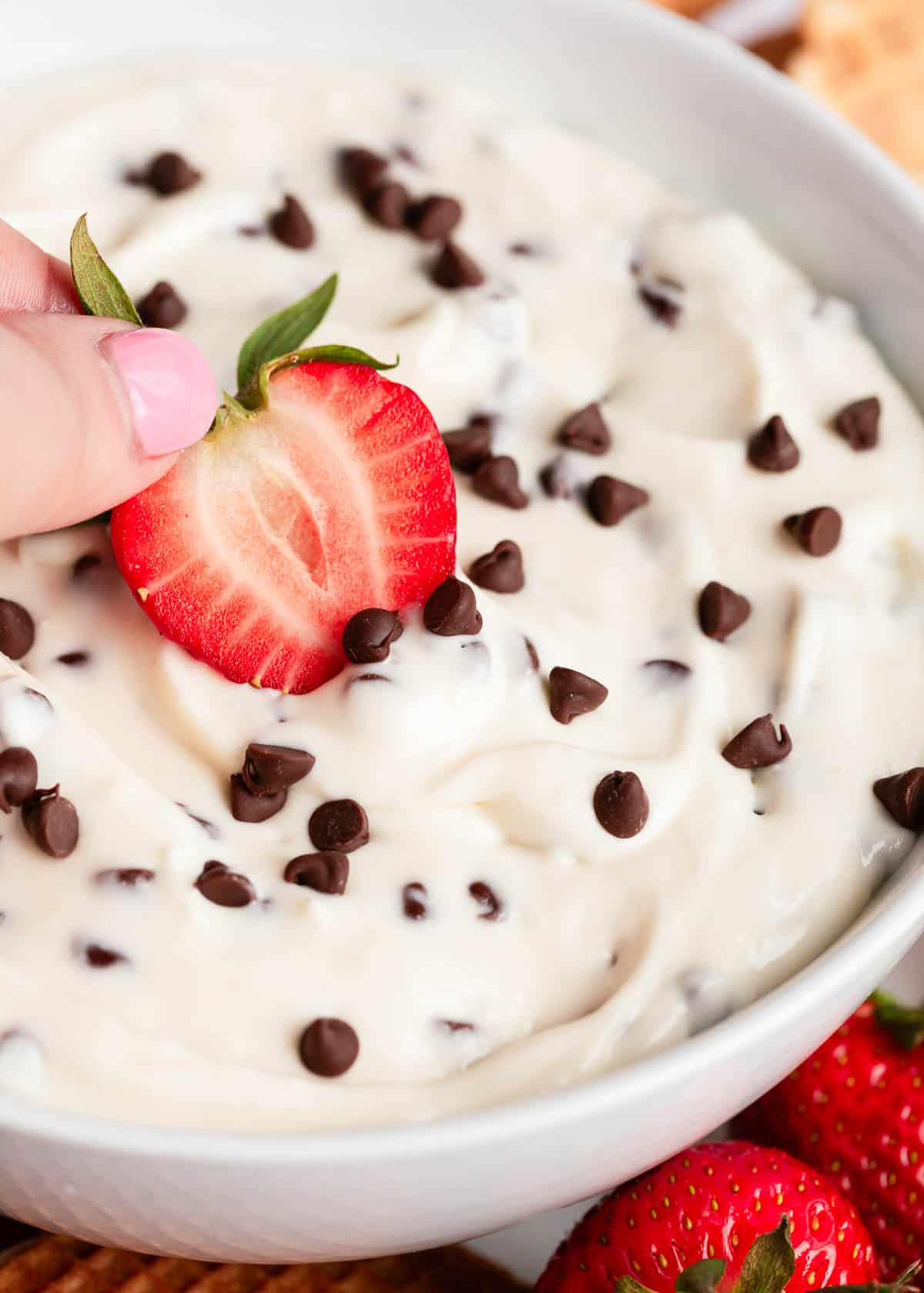 Dipping strawberry in cannoli dip.